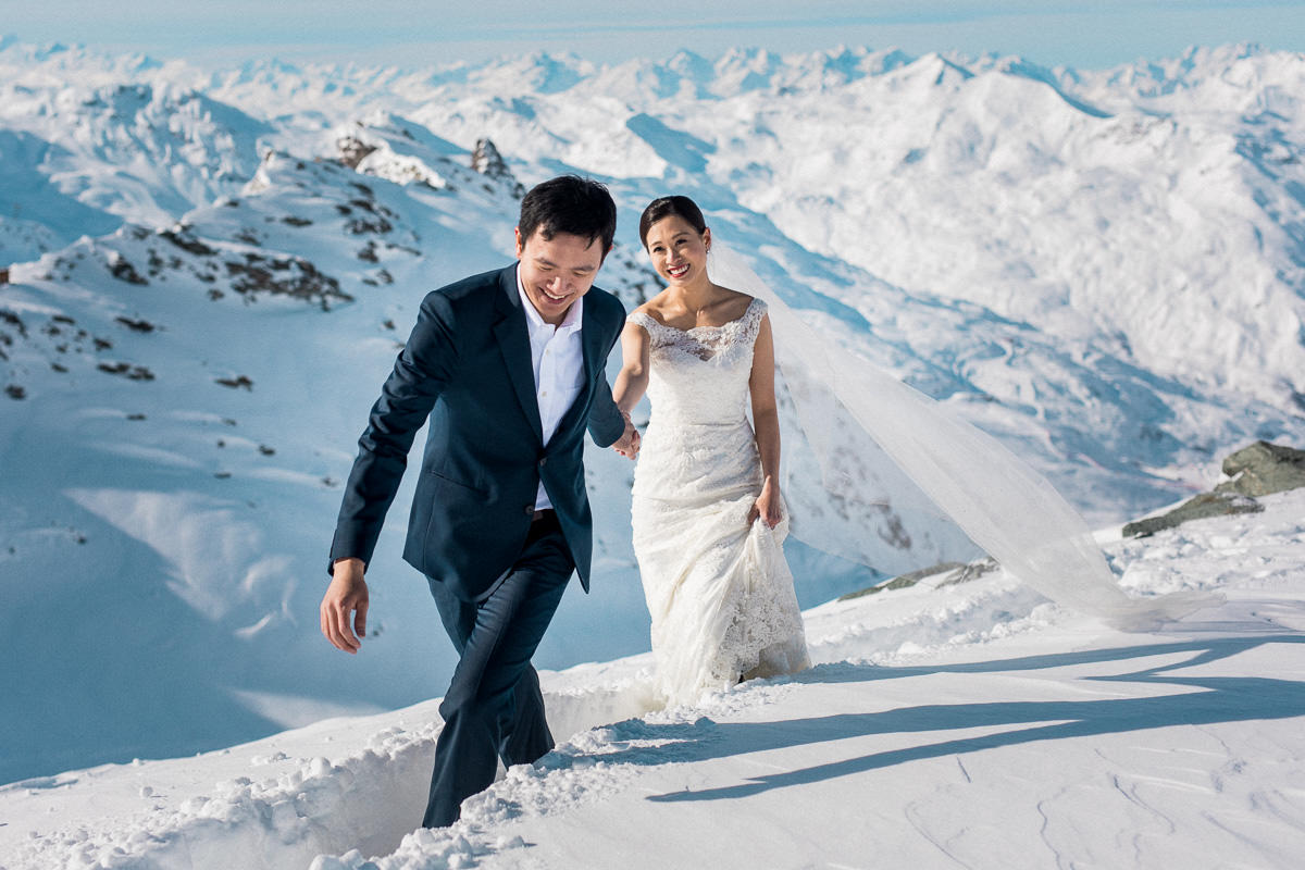 Des mariés lors de la session couple marchent dans la neige, capturé par le photographe mariage St Moritz Sylvain Bouzat