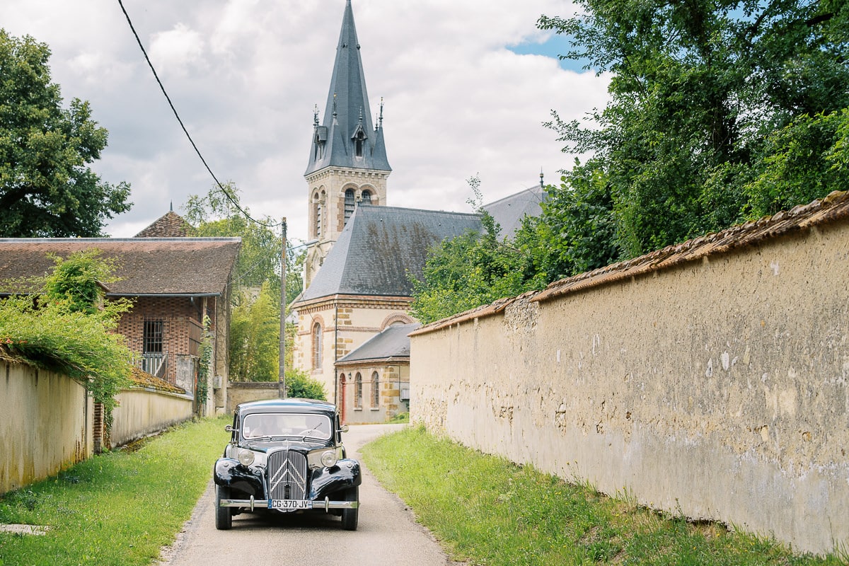Une ancienne voiture avec la belle mariée arrive au Château de Vallery pour la cérémonie.