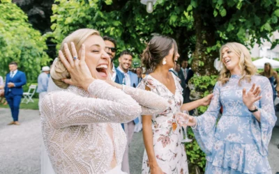 Joyful bride laughing with guests in a garden captured by a Geneva wedding photographer.