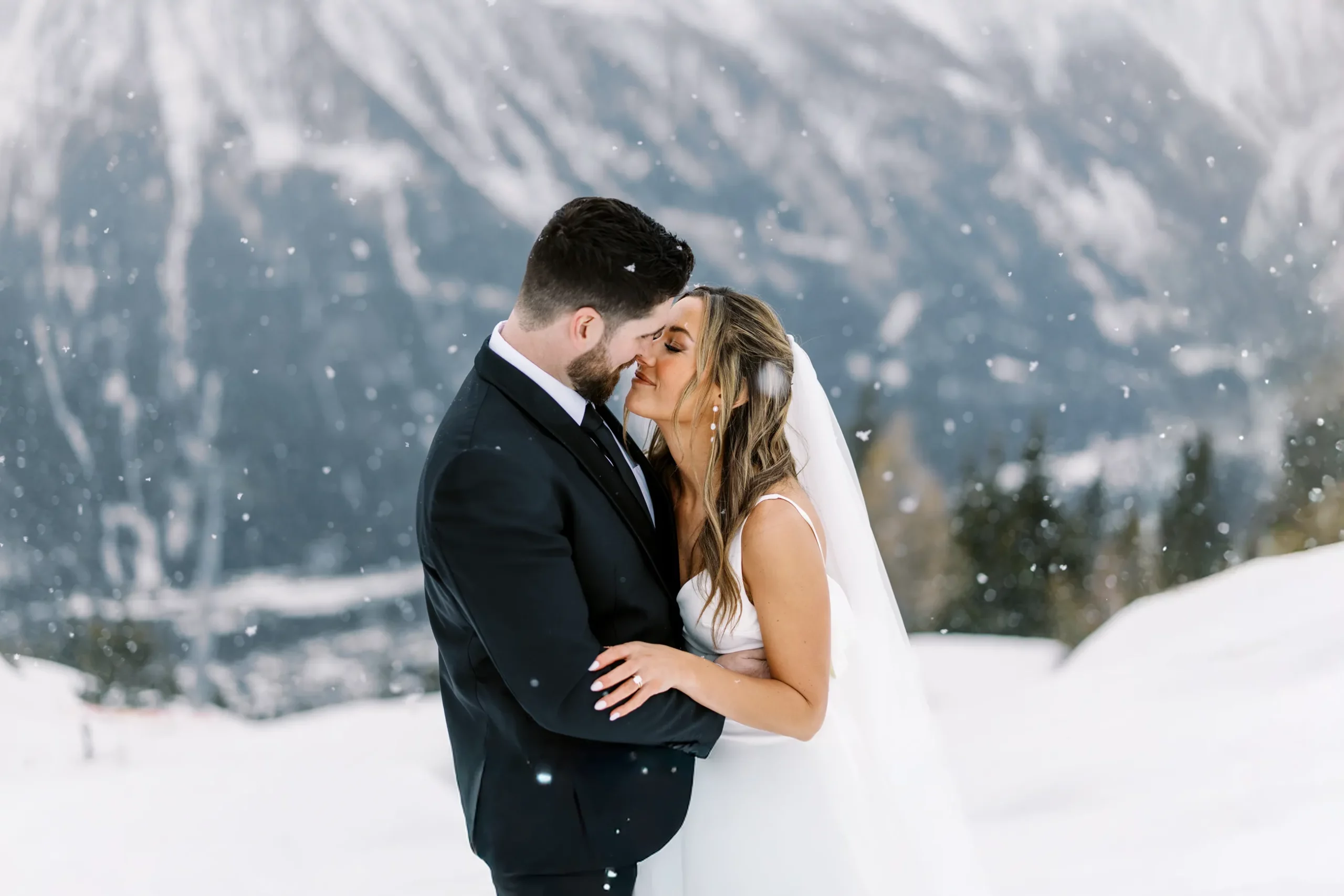 A bride and groom share an intimate moment in the falling snow, a romantic portrait by their wedding photographer in Chamonix, French Alps.