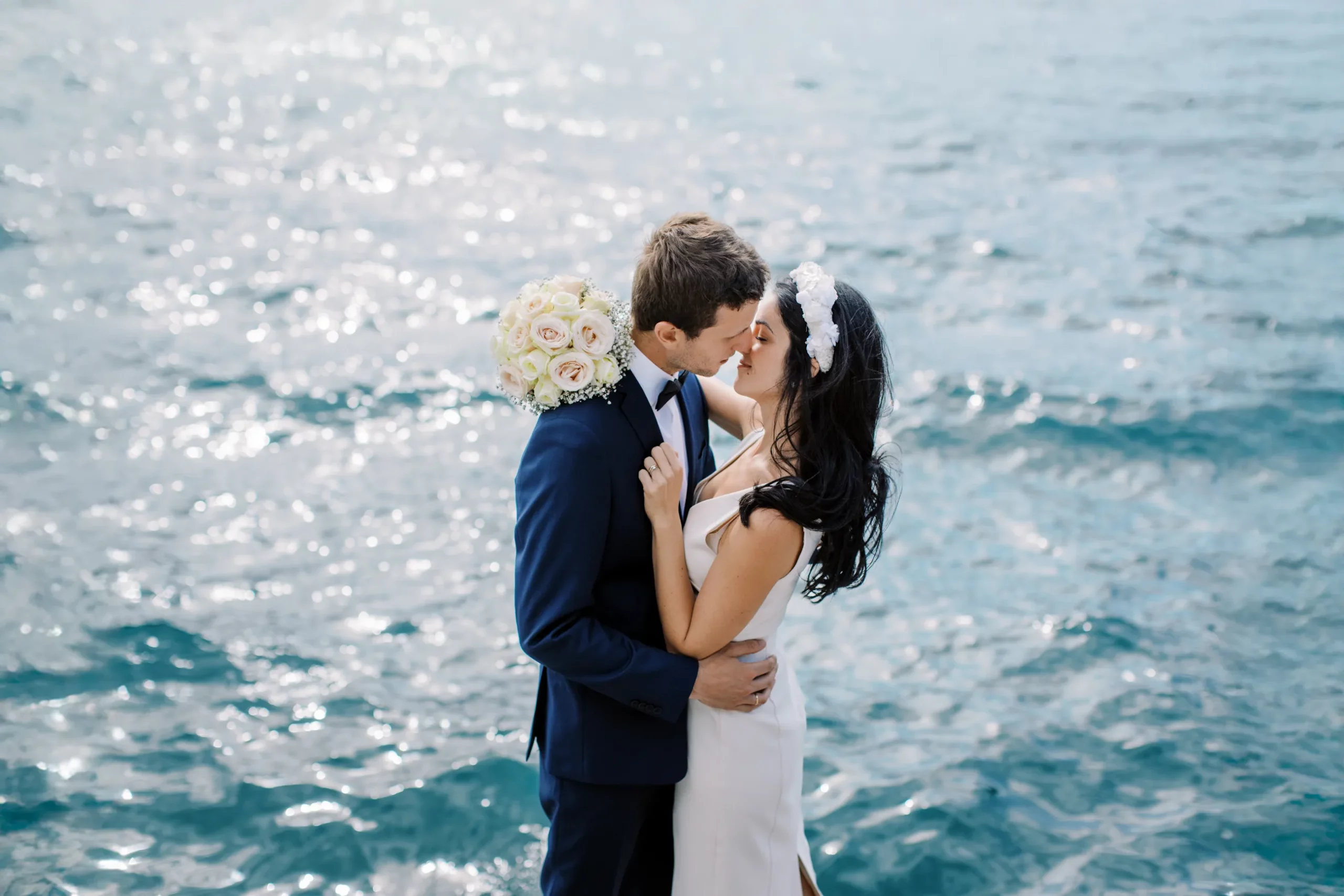 A bride and groom share a romantic kiss by the sparkling water of Lake Geneva, captured by their wedding photographer in Geneva.