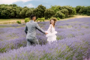 Bride looking back and smiling while groom leads her through a vibrant lavender field in Provence - captured by wedding photographer Provence.