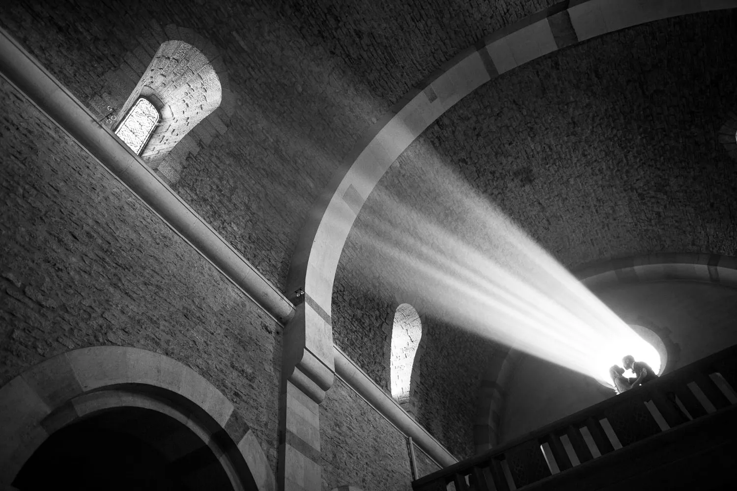 Dramatic black and white photo of a couple silhouetted in church light beams, possibly in Provence - artistic wedding photographer Provence.