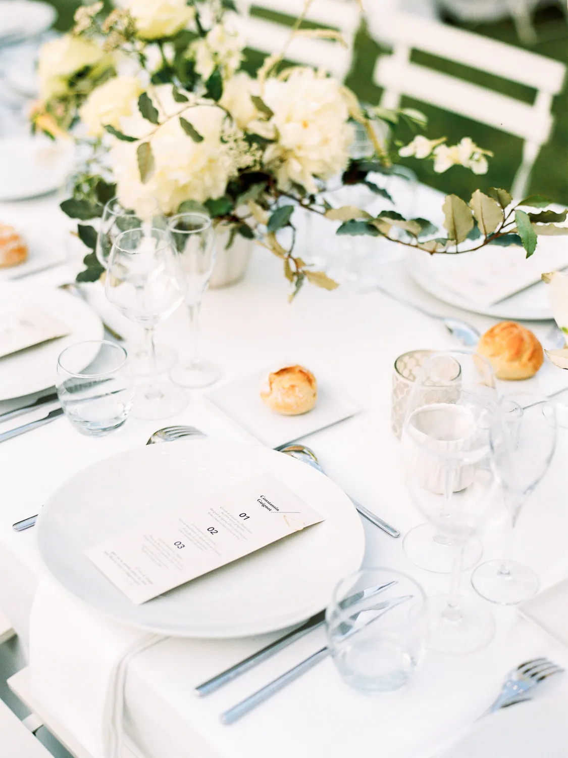 Chic white outdoor wedding table setting with menu and floral centerpiece on the French Riviera - photo by wedding photographer French Riviera.