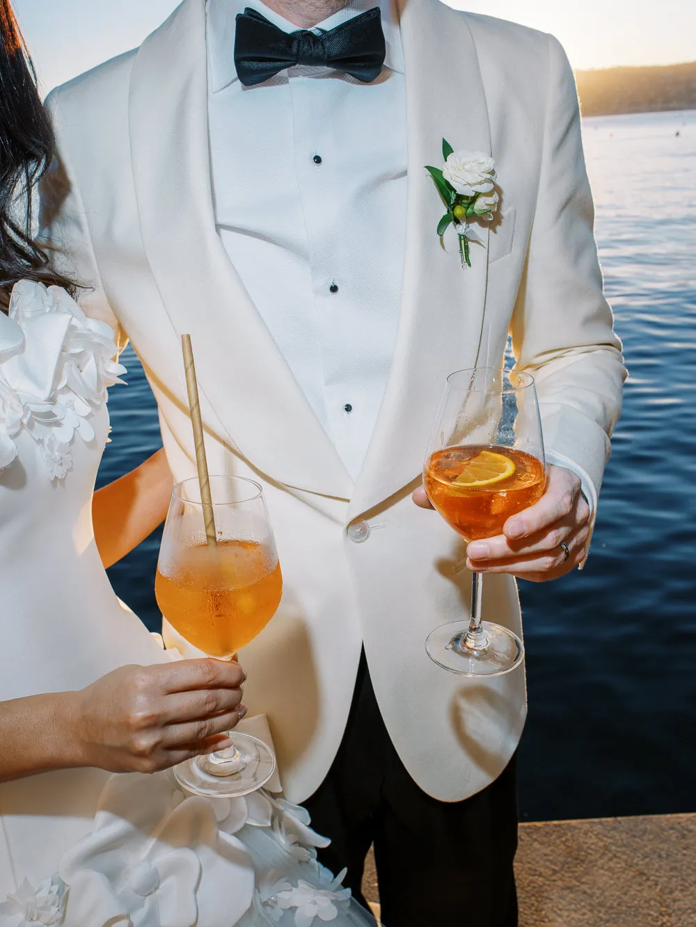 Stylish bride and groom holding Aperol Spritz cocktails by Lake Geneva - wedding photographer Geneva lifestyle shot.