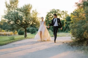 A bride and groom stroll down a scenic country path in Tuscany, captured by a wedding photographer in Italy.