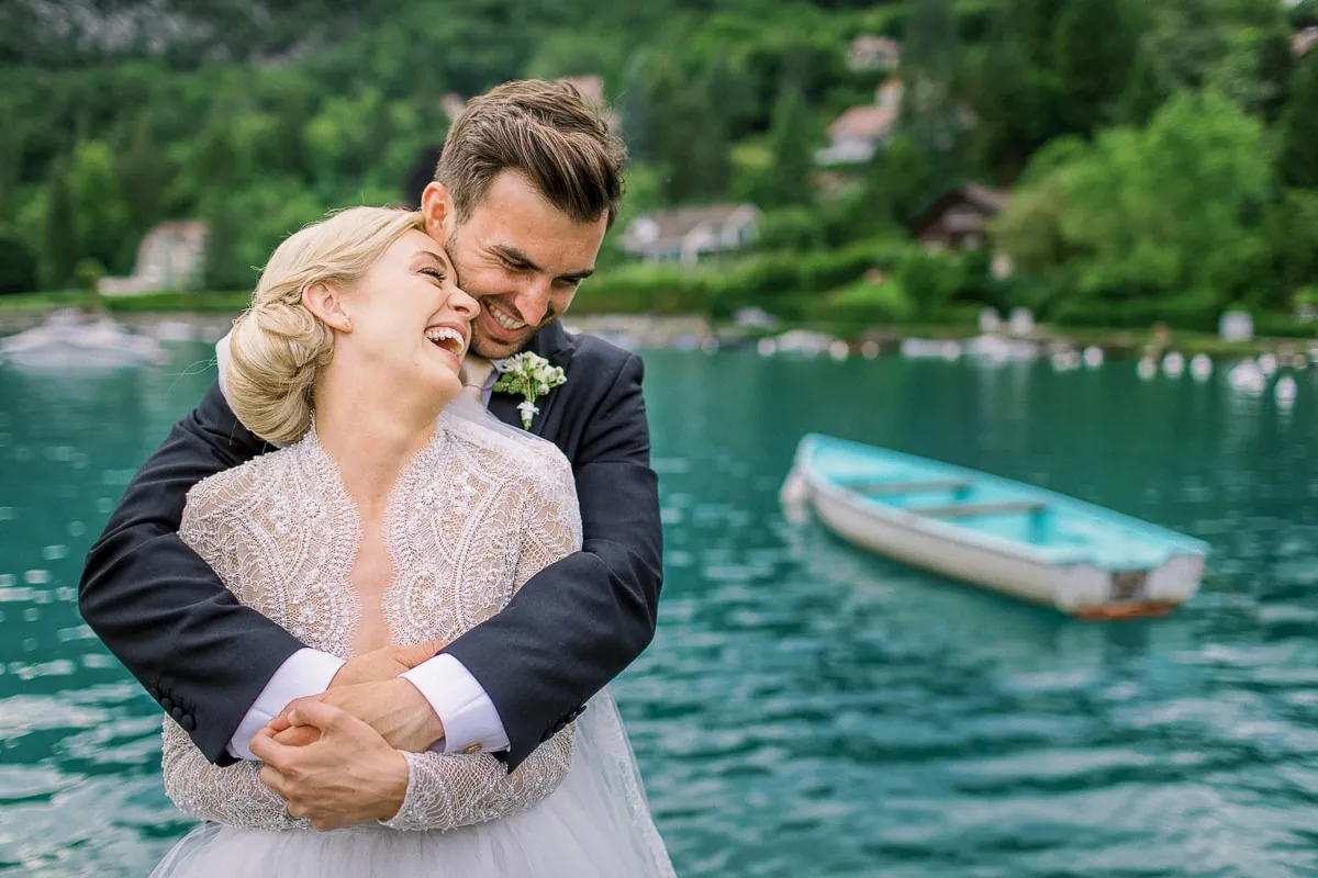 Joyful couple embracing and laughing by Lake Geneva in Lausanne - photo by lausanne wedding photographer.