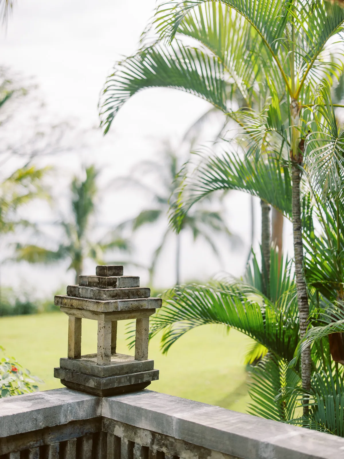 Traditional stone lantern detail amidst lush palm trees at a Lombok wedding venue - atmosphere shot by wedding photographer Lombok.