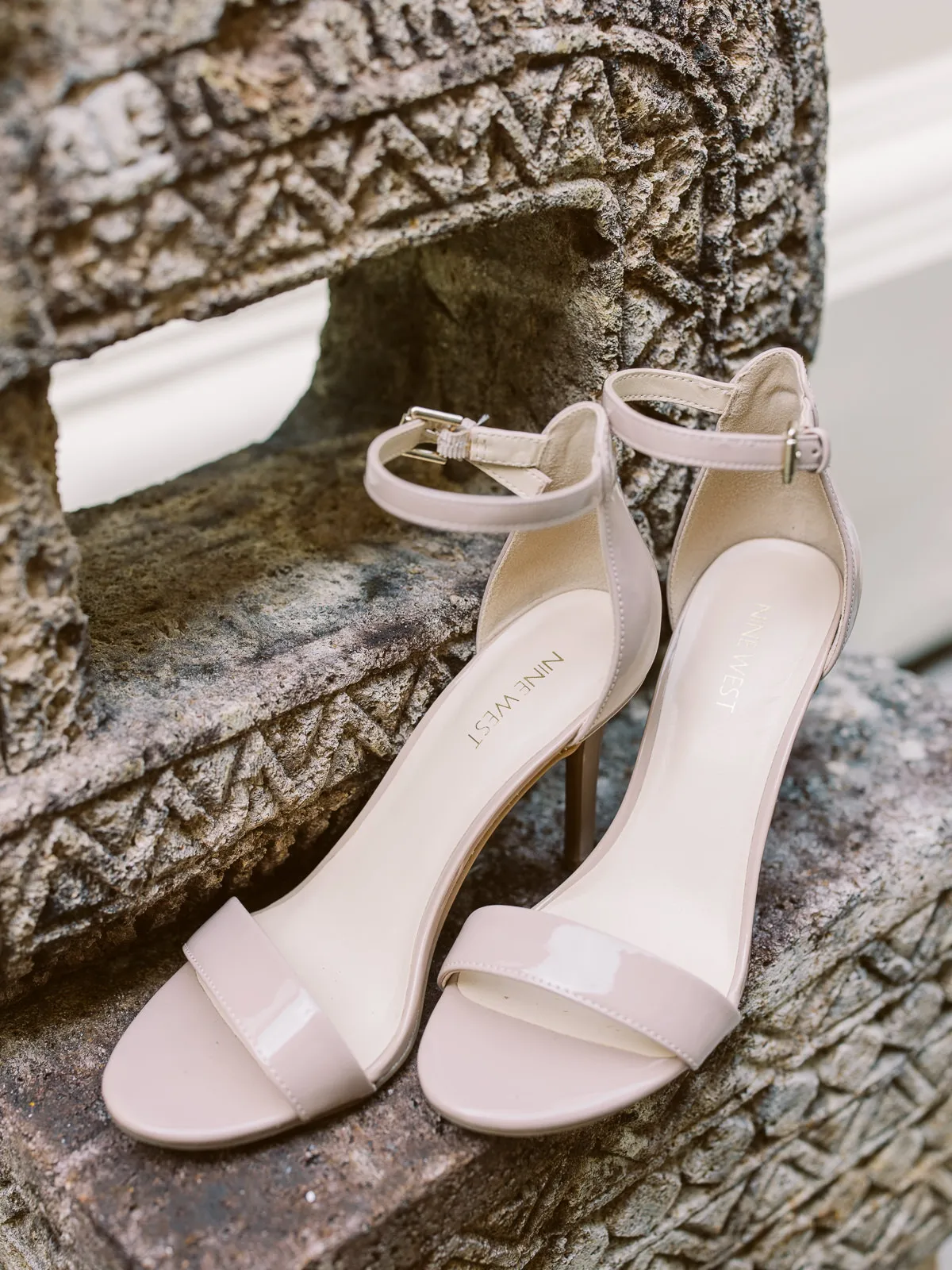 Nude Nine West bridal heels resting on carved stone detail at a Lombok wedding - photo by wedding photographer Lombok.