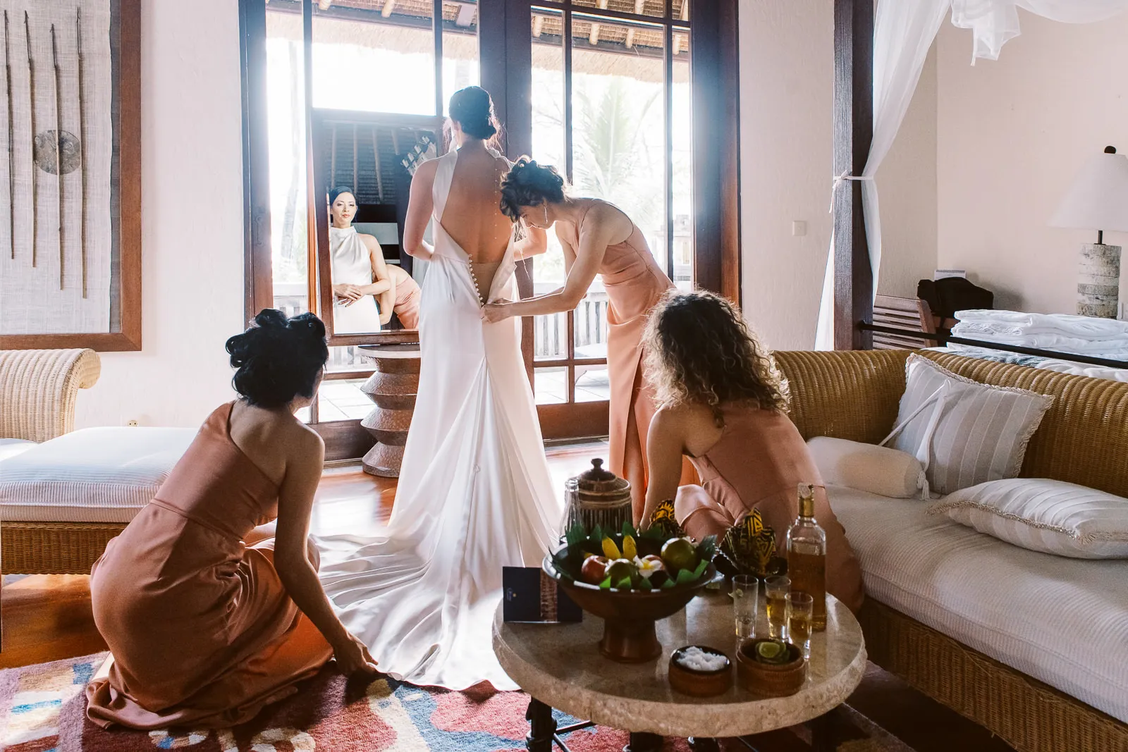 Bridesmaids helping bride into her elegant halter neck wedding dress in a Lombok villa - photo by wedding photographer Lombok.