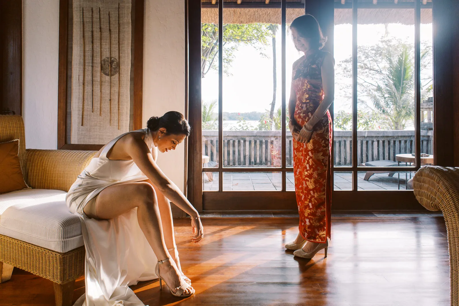 Bride sitting putting on her wedding shoes, mother in traditional dress looks on - Lombok wedding photo by wedding photographer Lombok.