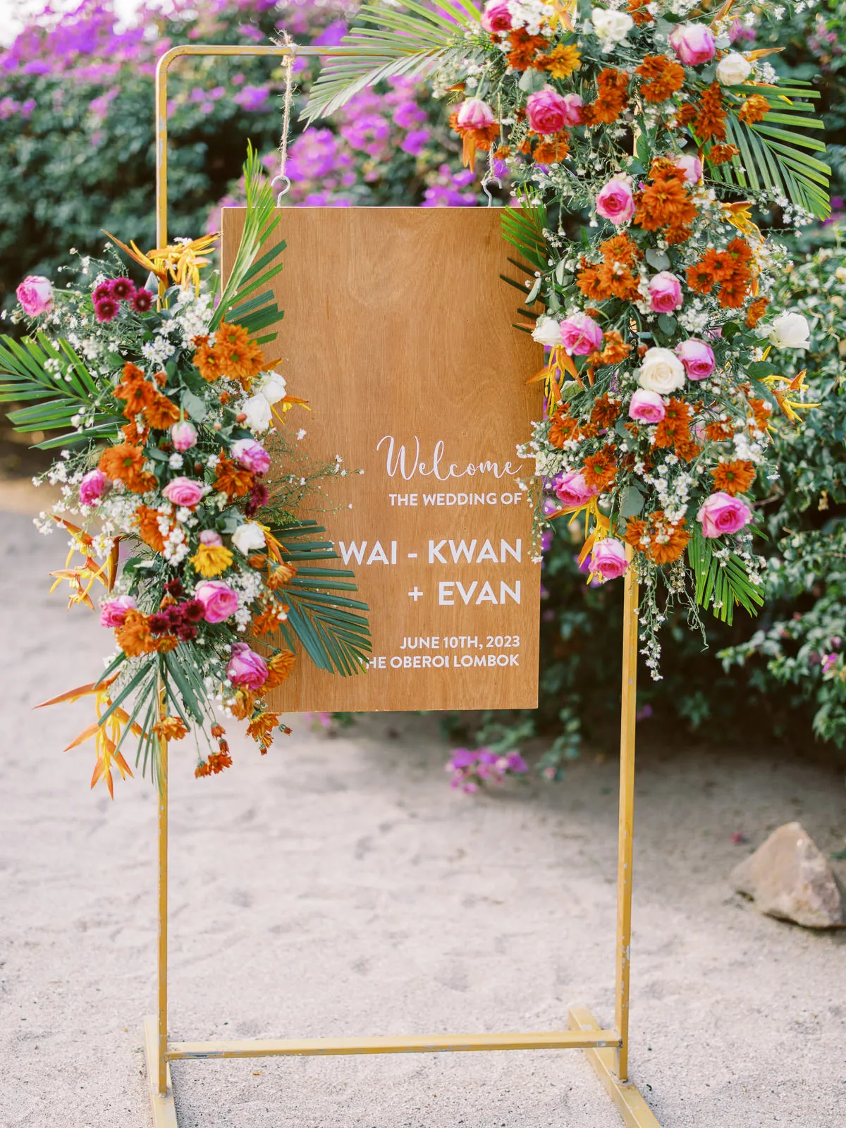 Wooden wedding welcome sign decorated with tropical flowers for Wai-Kwan + Evan's Lombok wedding - photo by wedding photographer Lombok.