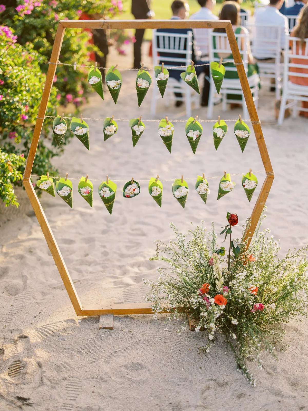 Wooden hexagonal frame holding leaf cones filled with flower petal confetti for Lombok beach wedding - detail by wedding photographer Lombok.