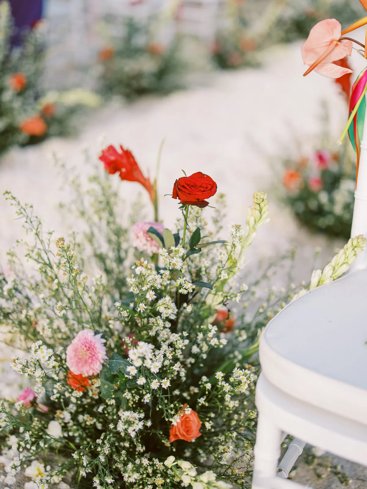 Colorful wedding ceremony aisle flowers including red roses and baby's breath on the beach in Lombok - photo by wedding photographer Lombok.