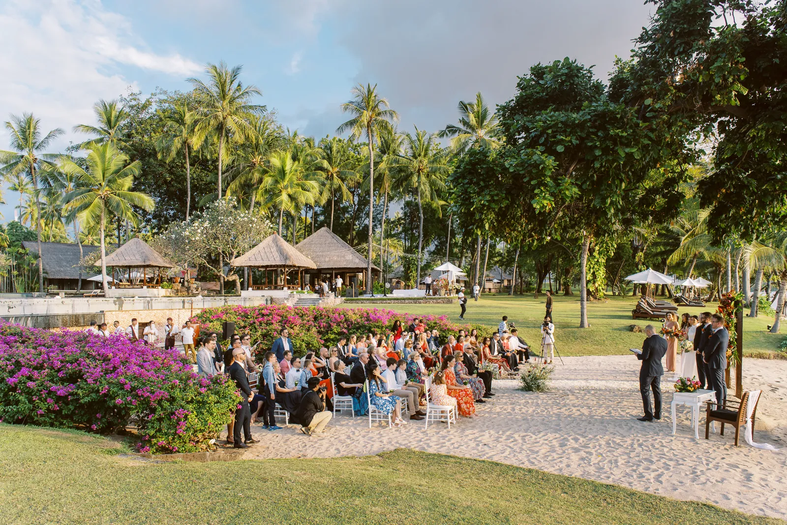 Wide view of outdoor beach wedding ceremony setup at The Oberoi Lombok with guests and ocean view - photo by wedding photographer Lombok.