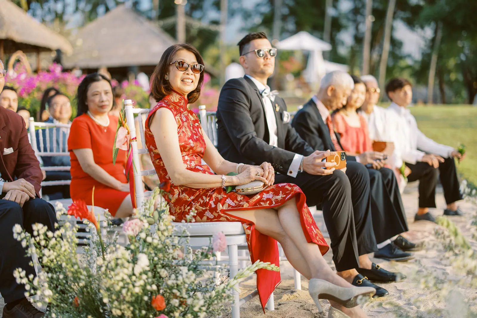 Stylish mother of the bride in traditional red dress watching Lombok wedding ceremony - photo by wedding photographer Lombok.