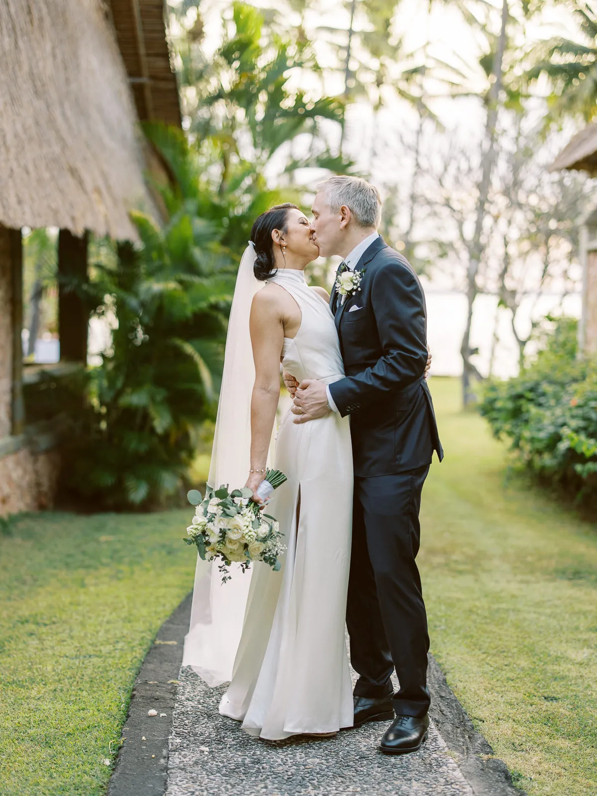 Bride and groom kissing on a garden path at their Lombok wedding venue - photo by wedding photographer Lombok.