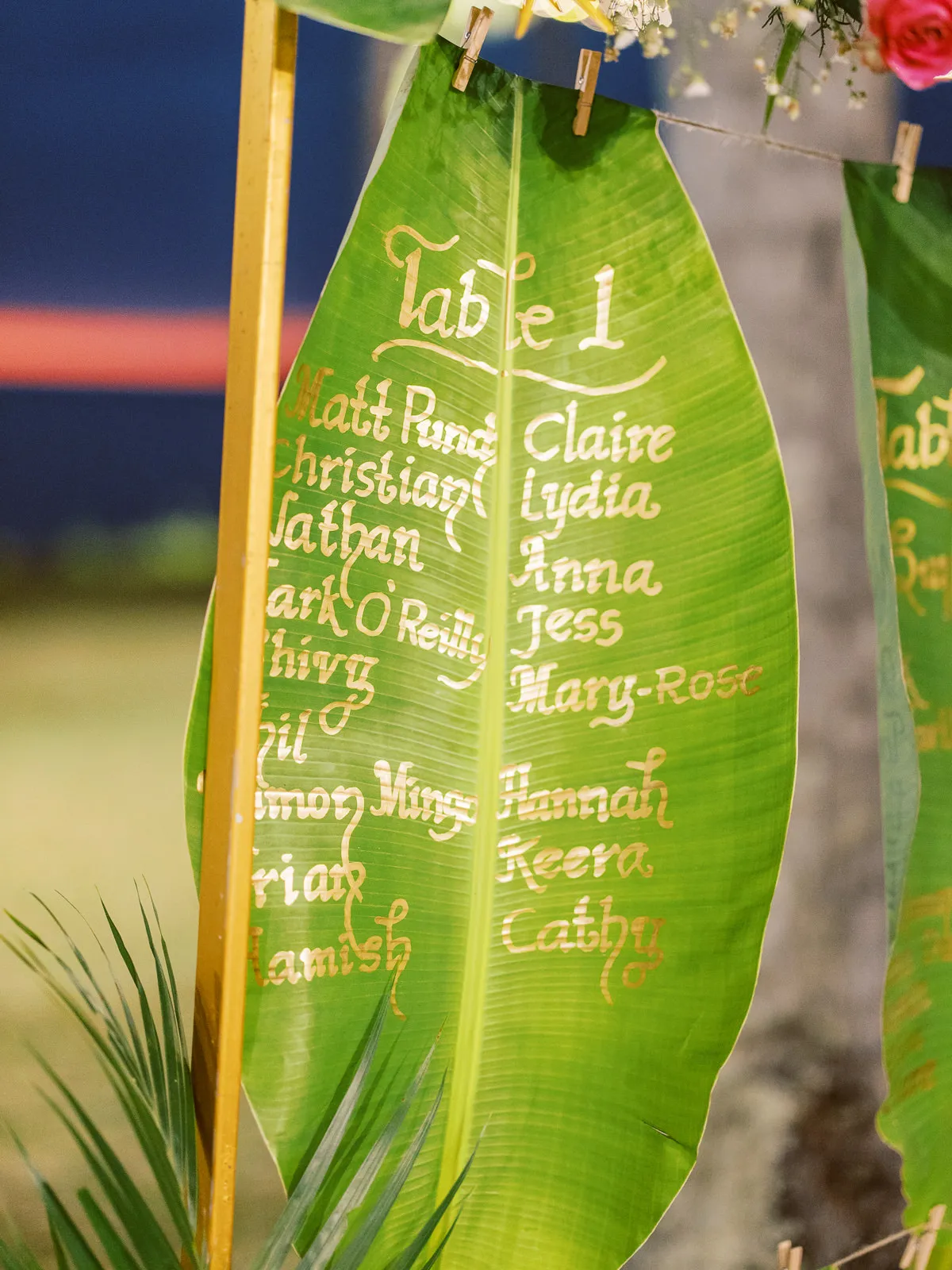 Close-up of wedding seating chart written in gold on a large banana leaf in Lombok - detail by wedding photographer Lombok.
