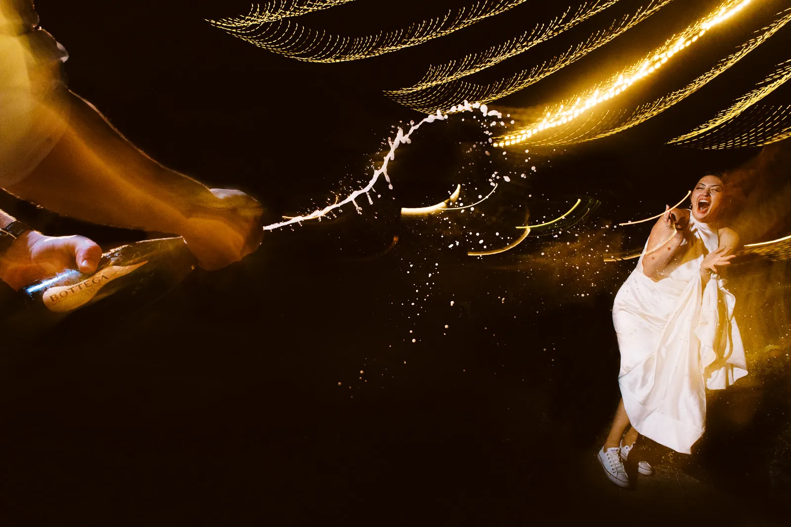 Bride reacting joyfully as champagne is sprayed explosively at Lombok wedding party - photo by wedding photographer Lombok.