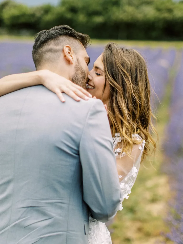 An intimate, over-the-shoulder view of a bride and groom about to share a kiss in the middle of a lavender field in the Luberon. Lavender couple photo.