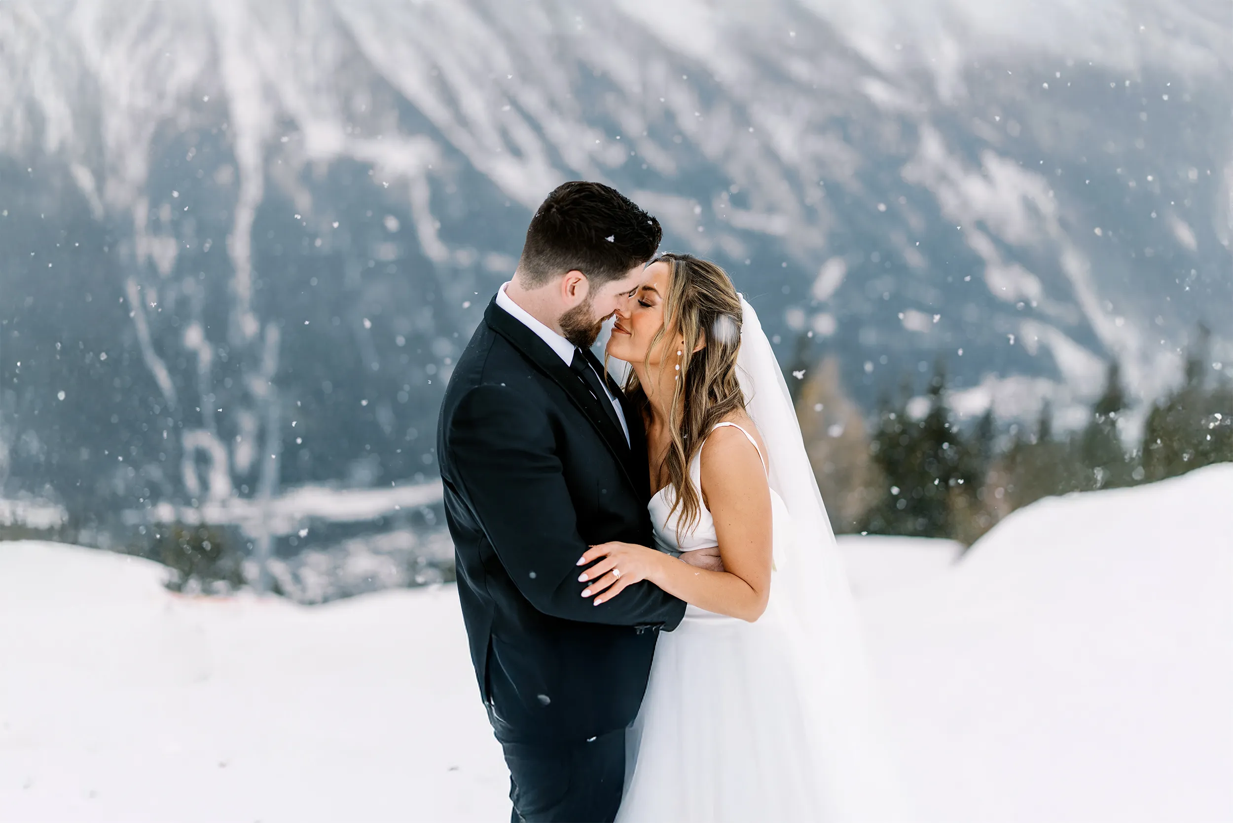 A bride and groom share an intimate moment in the falling snow, a romantic portrait by their wedding photographer in Megeve, French Alps.