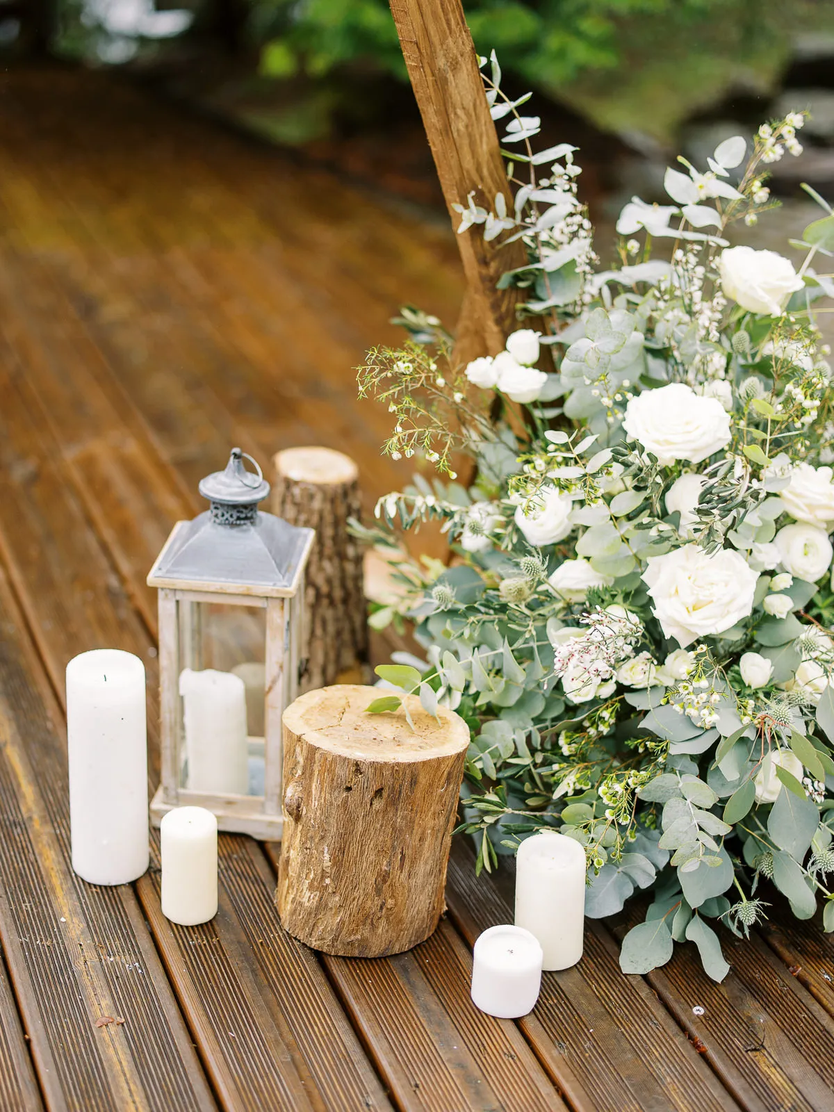 Rustic ceremony decor with lanterns, candles, and wood stumps on a deck, setting a romantic scene for a Megeve wedding.