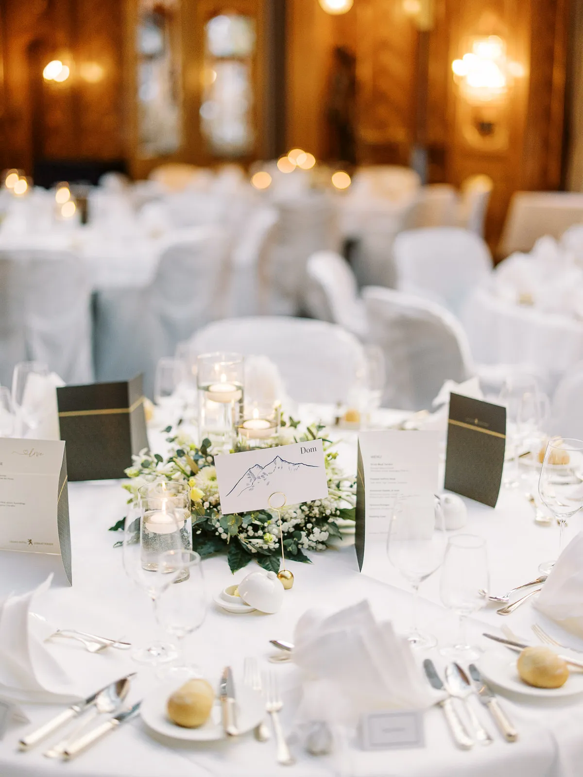 An elegant wedding reception table in Megeve, featuring a mountain-themed place card and floral centerpiece, captured by a French Alps wedding photographer.