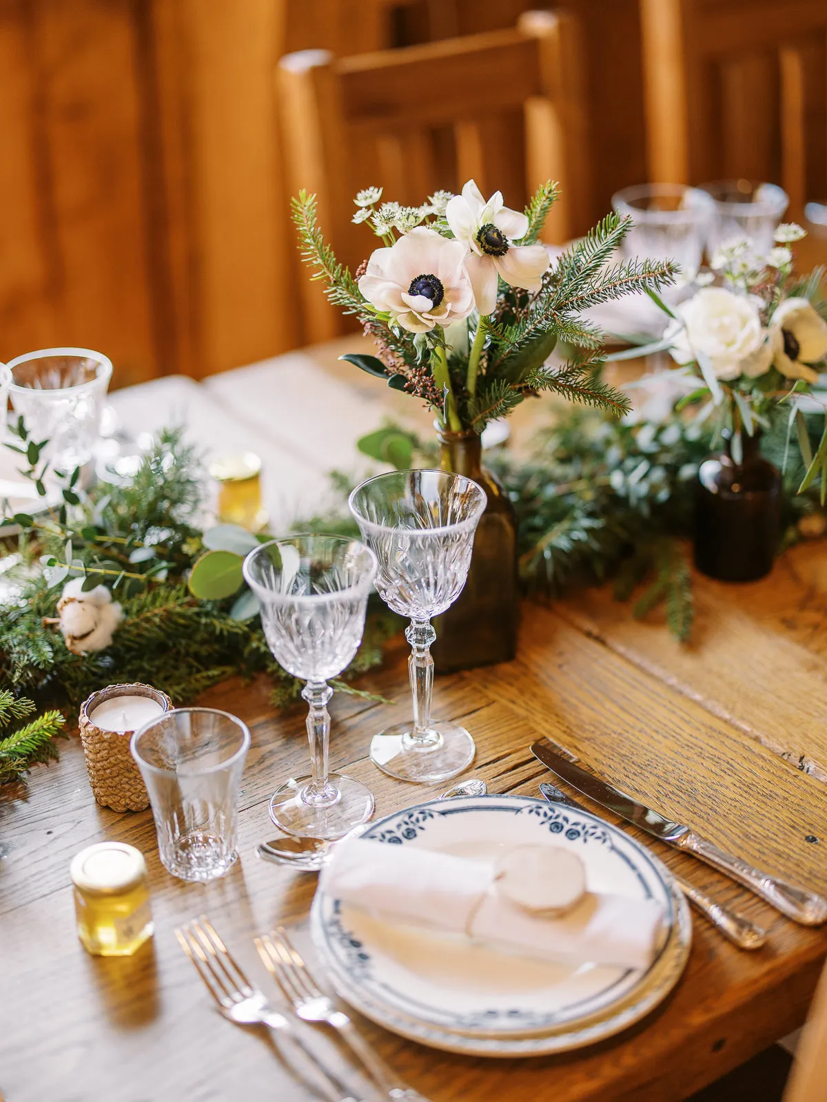 A rustic-chic wedding table setting in a Megeve chalet with anemones and pine greenery, a detail shot by a French Alps wedding photographer.