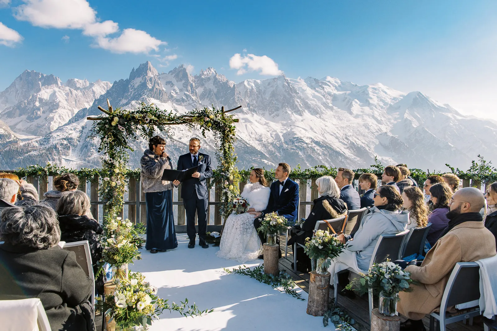 A spectacular outdoor winter wedding ceremony in Megeve with guests watching the couple against the epic backdrop of the snow-covered French Alps.