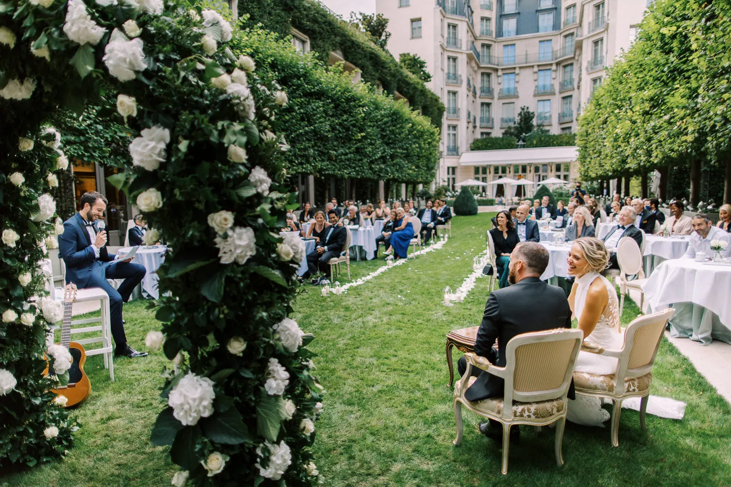 Elegant outdoor wedding ceremony in a lush garden courtyard, possibly at the Ritz Paris - captured by wedding photographer Ritz Paris. Photographe mariage Ritz Paris