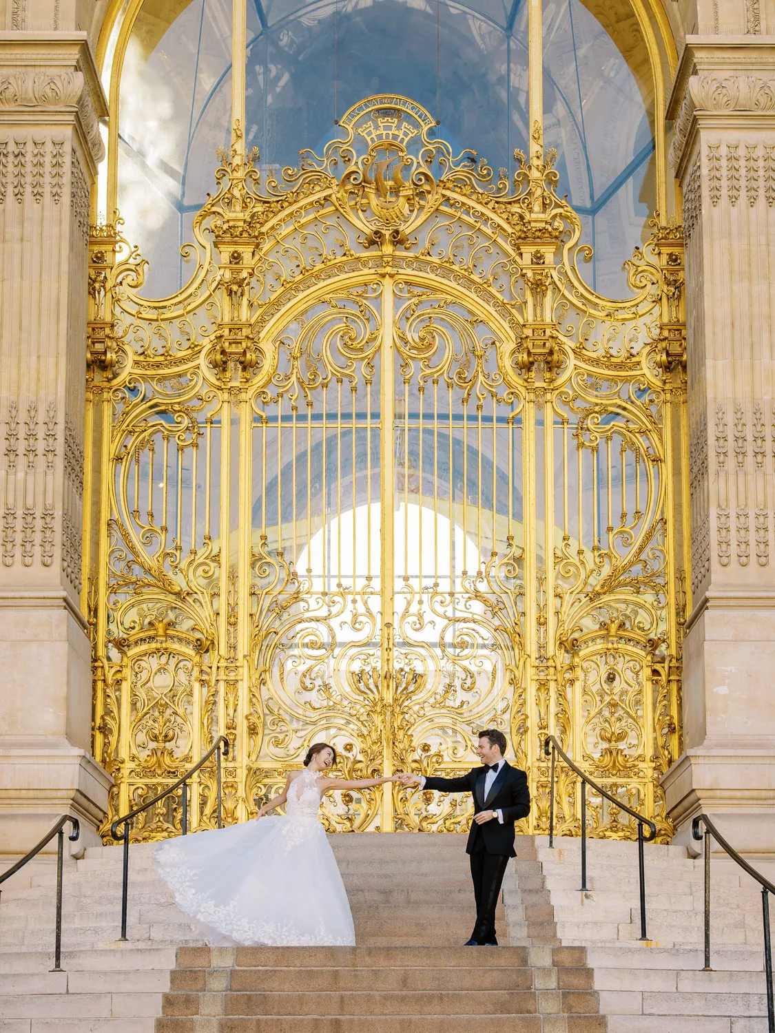 Bride and groom holding hands in front of the magnificent golden gates of the Petit Palais, Paris - by Wedding photographer Ritz Paris. Photographe mariage Ritz Paris