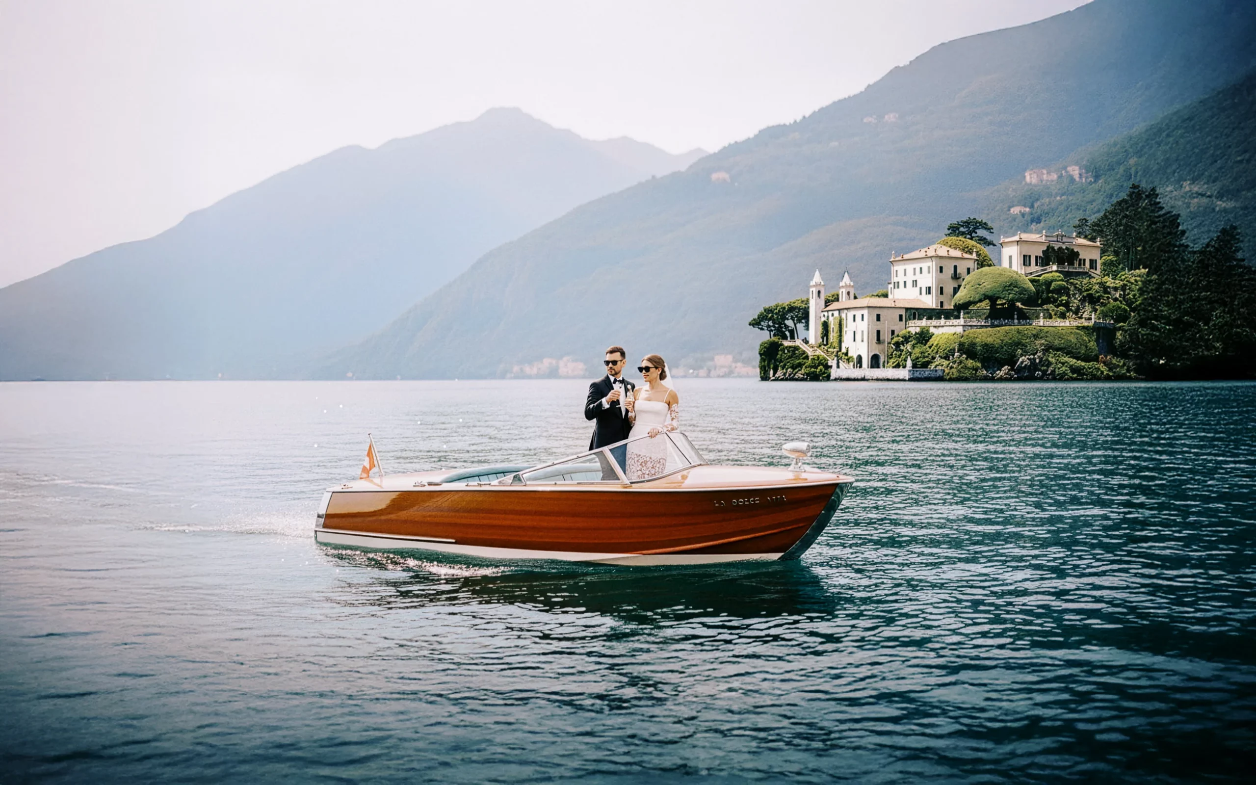 Elegant couple on a classic wooden boat celebrating on Lake Como, captured by a wedding photographer Lake Como.