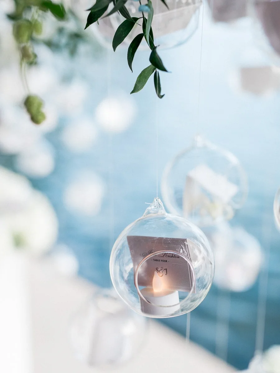 Elegant hanging glass orbs with flickering lights and place cards by a wedding photographer Lake Como.