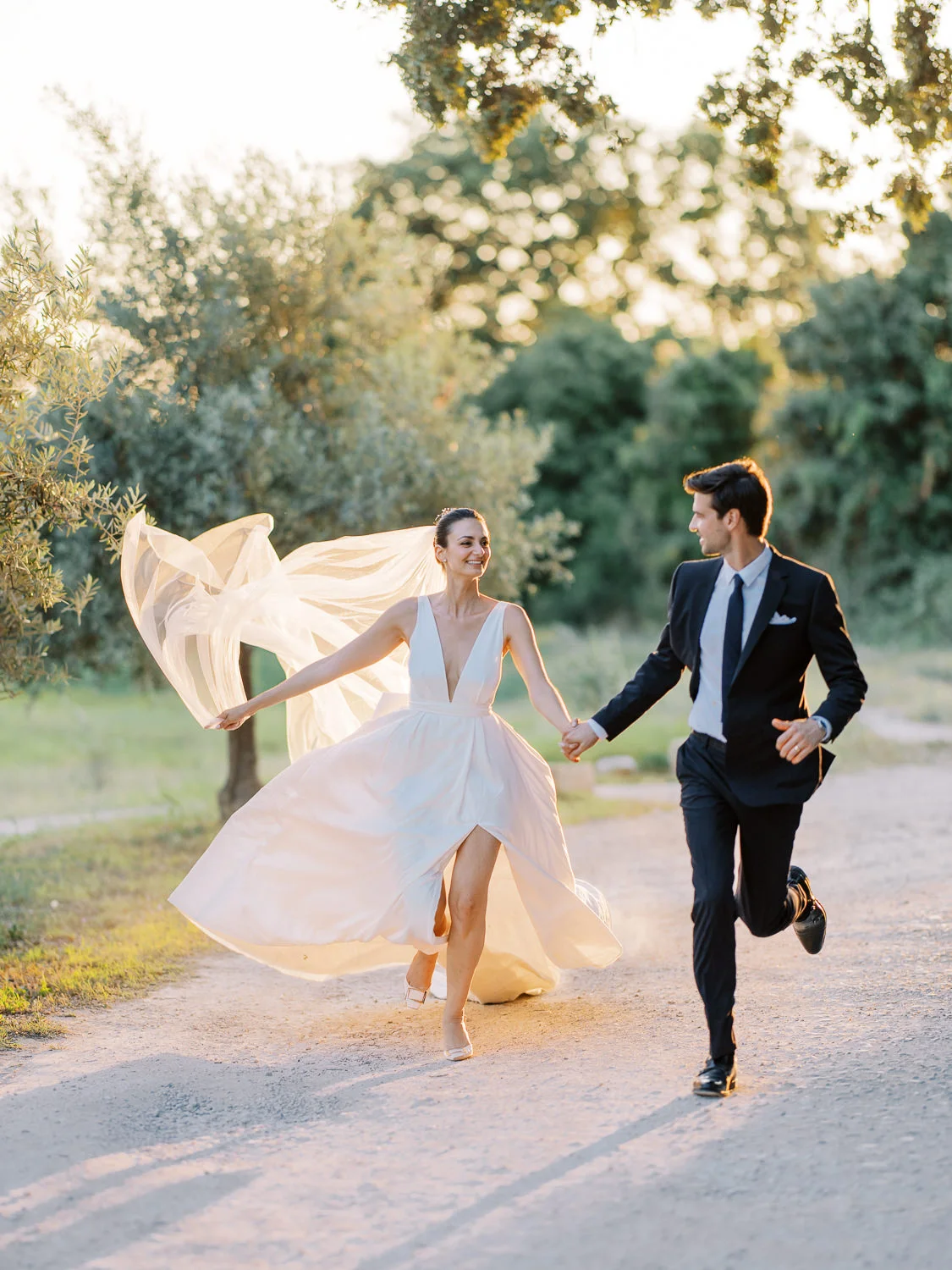 Joyful bride and groom running on a sunny path, captured by a Wedding photographer Lake Como. Photographe Mariage Lac de Côme.