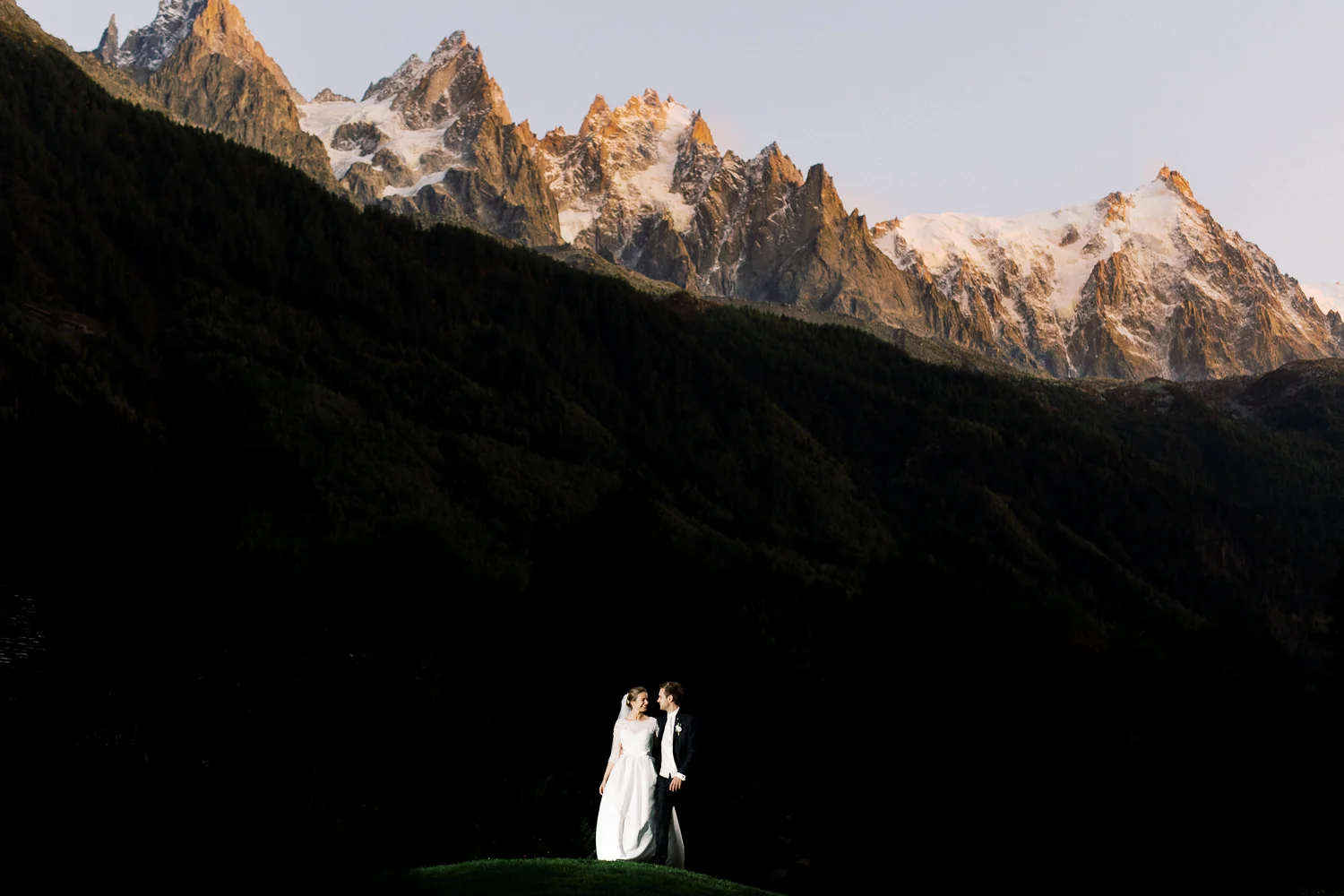 Couple in a dramatic light beam against Alpine peaks captured by Davos wedding photographer. Photographe mariage Davos.