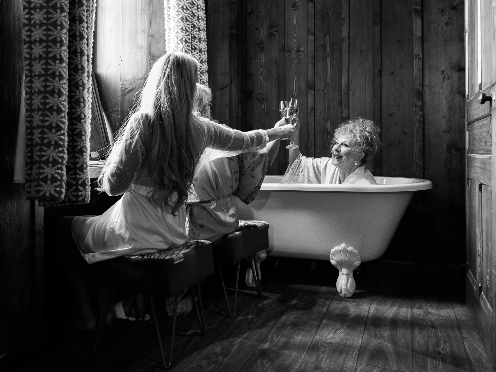 Joyful toast between two women in a luxurious wooden bathroom by Wedding photographer Crans-Montana.