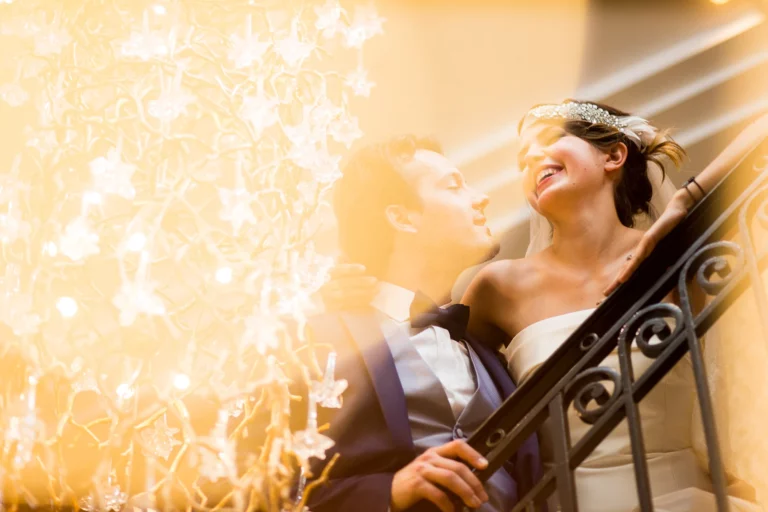 Joyful bride and groom on a grand staircase by a french wedding photographer.