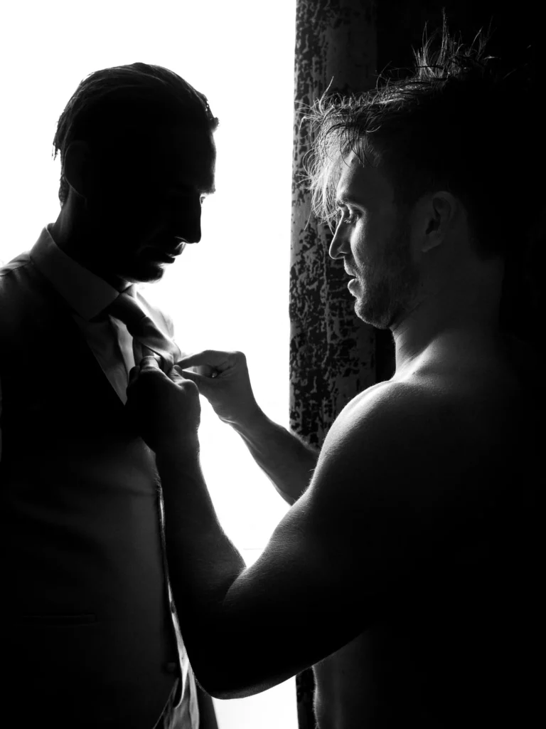 Silhouette of groom prep by a French wedding photographer in a luxury hotel suite.
