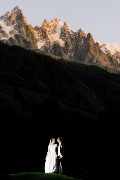 Bride and groom portrait against sunlit Alpine peaks by a French wedding photographer.