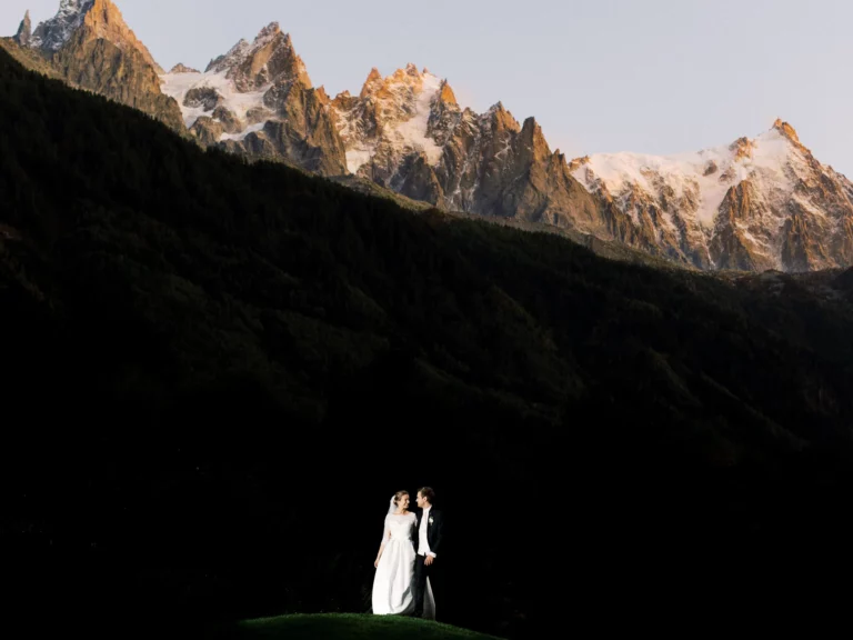 Bride and groom portrait against sunlit Alpine peaks by a French wedding photographer.