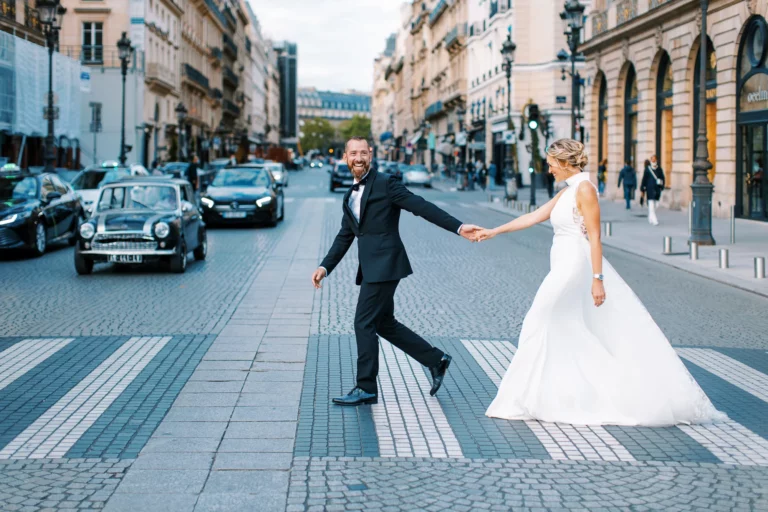 A joyful bride and groom crossing a Parisian street by a French wedding photographer.
