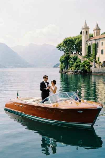 Couple toasting on a Riva boat at Lake Como. French wedding photographer.