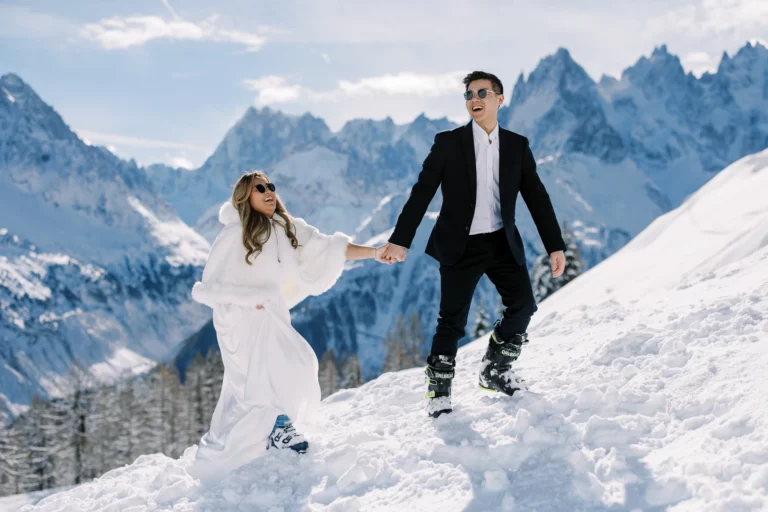 Couple radieux en tenue de mariés et chaussures de ski capturé par un photographe de mariage.