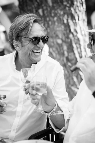 Candid black and white photo of men laughing with cigars by a French wedding photographer.