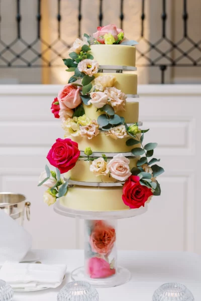 Elegant multi-tiered yellow cake with fresh roses captured by a French wedding photographer.