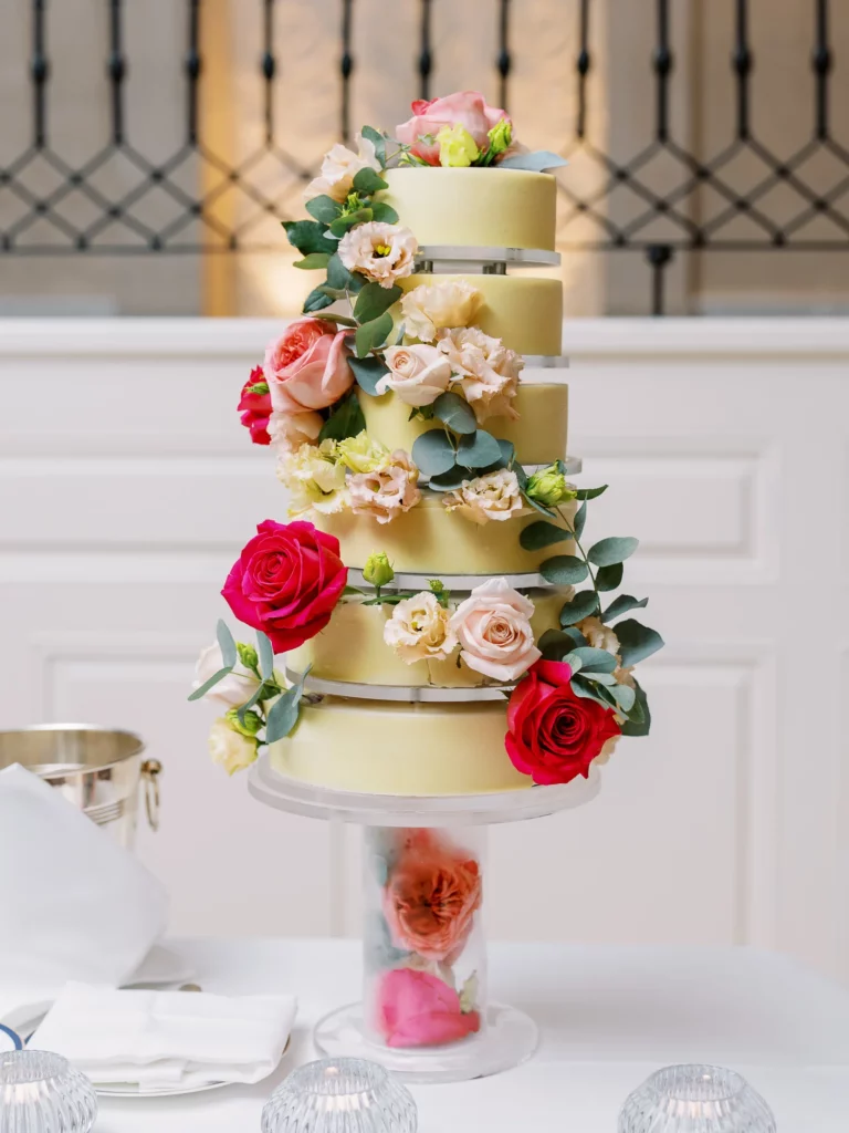 Elegant multi-tiered yellow cake with fresh roses captured by a French wedding photographer.