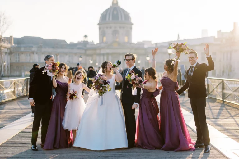 A joyful bride drinking champagne on a Paris bridge with a French wedding photographer capturing the moment.