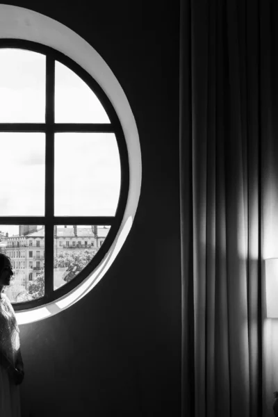 Silhouette of a bride by a grand circular window captured by a French wedding photographer.