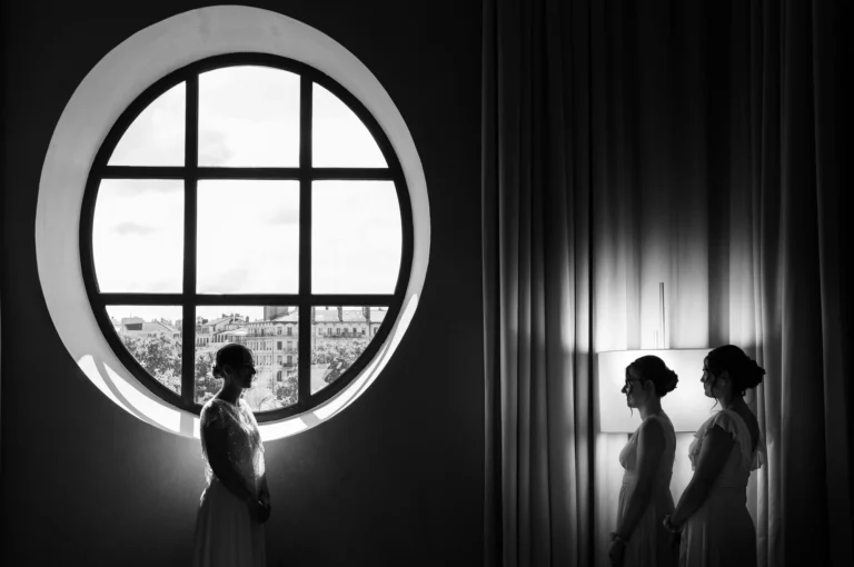Silhouette of a bride by a grand circular window captured by a French wedding photographer.