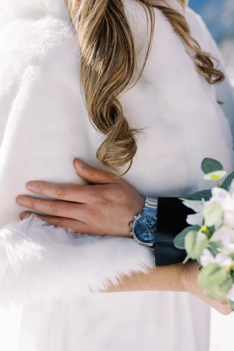 Main du marié sur le manteau en fourrure de la mariée lors d'un mariage d'hiver.